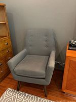 Front view of one chair showing upholstery, cushion, legs