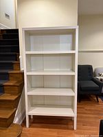 Front view of white bookcase showing four shelves and raised legs