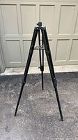 full view of black metal tripod stand on driveway