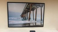 Front view of framed ocean pier photograph on wall
