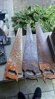 Three vintage hand saws laid out showing full blades and handles