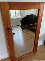 Full view of rectangular mirror with wooden frame leaning against wall