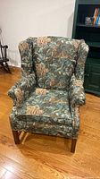 Front view of single wingback armchair showing upholstery and wooden legs