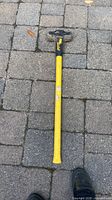 Full view of yellow fiberglass sledgehammer on paving stones
