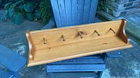 Front view of solid wood wall shelf with five pegs