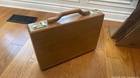 Overall view of wooden attaché showing handle, wood grain and combination latches