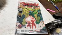 Front view of Deadpool #23 comic book in protective sleeve on tabletop