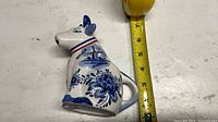 Left profile of Delft cow pitcher next to tape measure indicating height