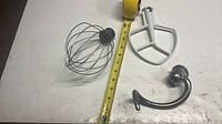 Wire whip, flat beater and dough hook with tape measure for scale
