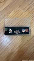 Five enamel lapel pins inside clear display case