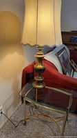 Full view of brass table lamp on glass table showing base, shade, and cord