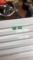 Two loose rectangular emeralds side by side on white surface