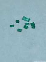 All eight loose emerald gemstones arranged on neutral background