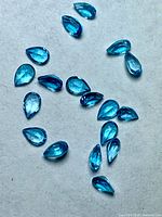 All 18 pear-cut blue topaz gemstones on neutral background