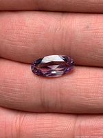 Faceted oval light purple amethyst on fingertip