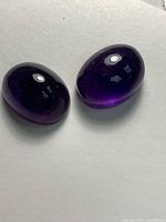 Two deep purple oval cabochons on light background