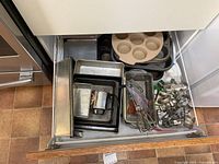 Drawer view showing pans, muffin tray, flour sifter and other bakeware