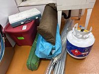 Group shot of stove, propane tank, fabric bags, poles and red tote