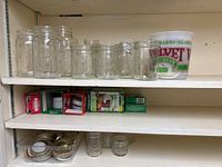 Shelved glass Mason jars, boxed lids, plastic tub on shelf