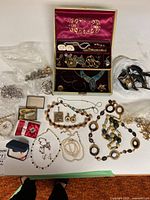 Overview of entire lot on table including jewelry box, necklaces, watches, earrings, bracelets