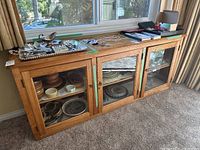 Front view of wooden glass hutch showing three doors and contents inside