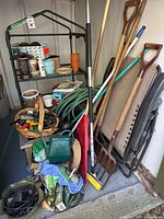 Overall lot showing long-handled tools, chair, hose, greenhouse stand and pots