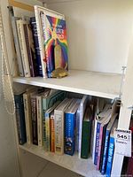 Two shelves of books with brass turtle on upper shelf