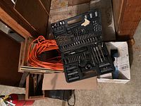 Group shot showing bit set, extension cord, wooden crates, fire extinguisher, cardboard box with towels