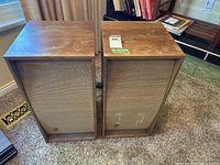 Front view of both speakers showing woven grilles and logo badges