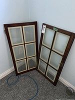 Pair of wood and glass pane doors leaning against wall