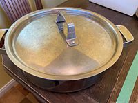 Closed shallow stainless pot with lid showing top view and handles