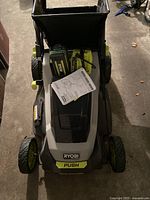 Top view of Ryobi 40V mower showing battery compartment, battery, charger and manual