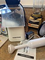 Toastess popcorn maker, Osterizer blender, immersion blender and manual visible