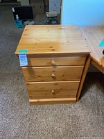 Front view showing three drawers and wooden pulls