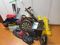 Overall view of lot showing bocce, croquet, dartboard, lifejackets, golf clubs, boots, bags
