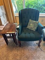 Front view of green armchair beside nested tables