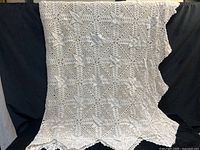 Full view of cream crochet twin bed cover hanging to show overall pattern and size