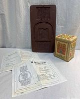 Front view of Hartstone cookie mold, instruction sheets and decorative tin