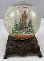 Full view of snow globe showing glass sphere and ornate metal base