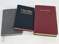 Front view of three Bibles: grey NASB, black NIV, burgundy NKJV