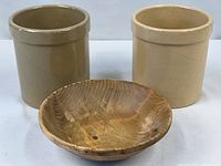 Two beige stoneware crocks and one ginkgo wood bowl grouped together