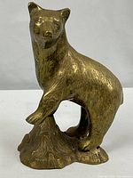 Full view of brass bear statue on rock base