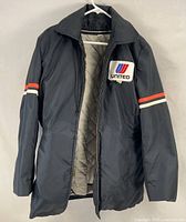 Front view of navy jacket on hanger showing logo patch and sleeve stripes