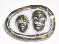 Front view showing carved faces and mottled stone.