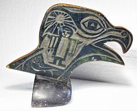 Left-facing view of carved bird head on stone base showing sun, human, fish motifs and overall form