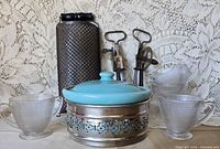 Group shot showing all items: casserole with cradle, glass pieces, egg beaters, grater