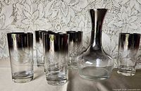 Front view of decanter and six tumblers showing silver fade design