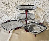 Four chrome trays displayed, showing both pedestal and tripod styles