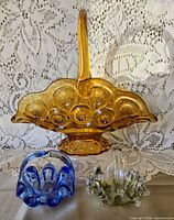 Front view of amber Moon & Stars basket with two miniature swung glass baskets (blue, green)