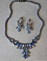 Necklace and earrings laid out flat showing full design